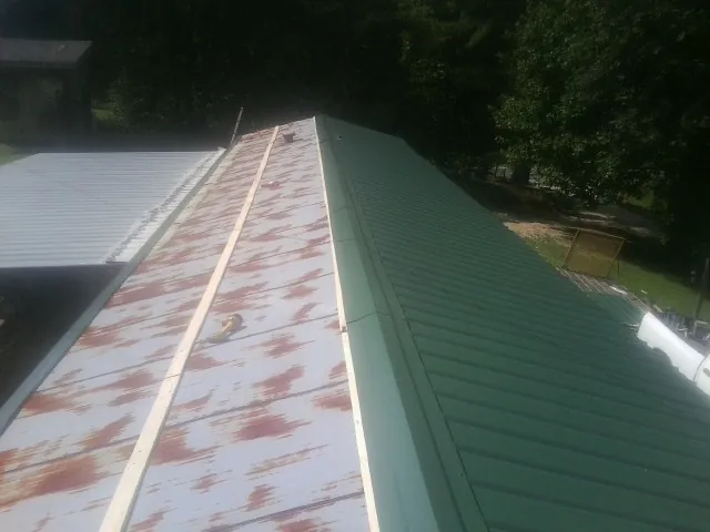 Old rusted panels beside newly installed green metal roofing — Wind Damage Roof Repair by Roofing Brothers in Maple Mount