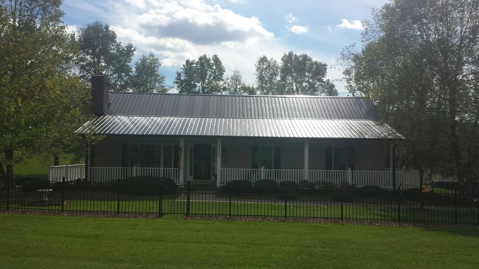 Gray metal roof on a brick ranch with a full width front porch — Gutter Guard Installation work by our crew in Maple Mount