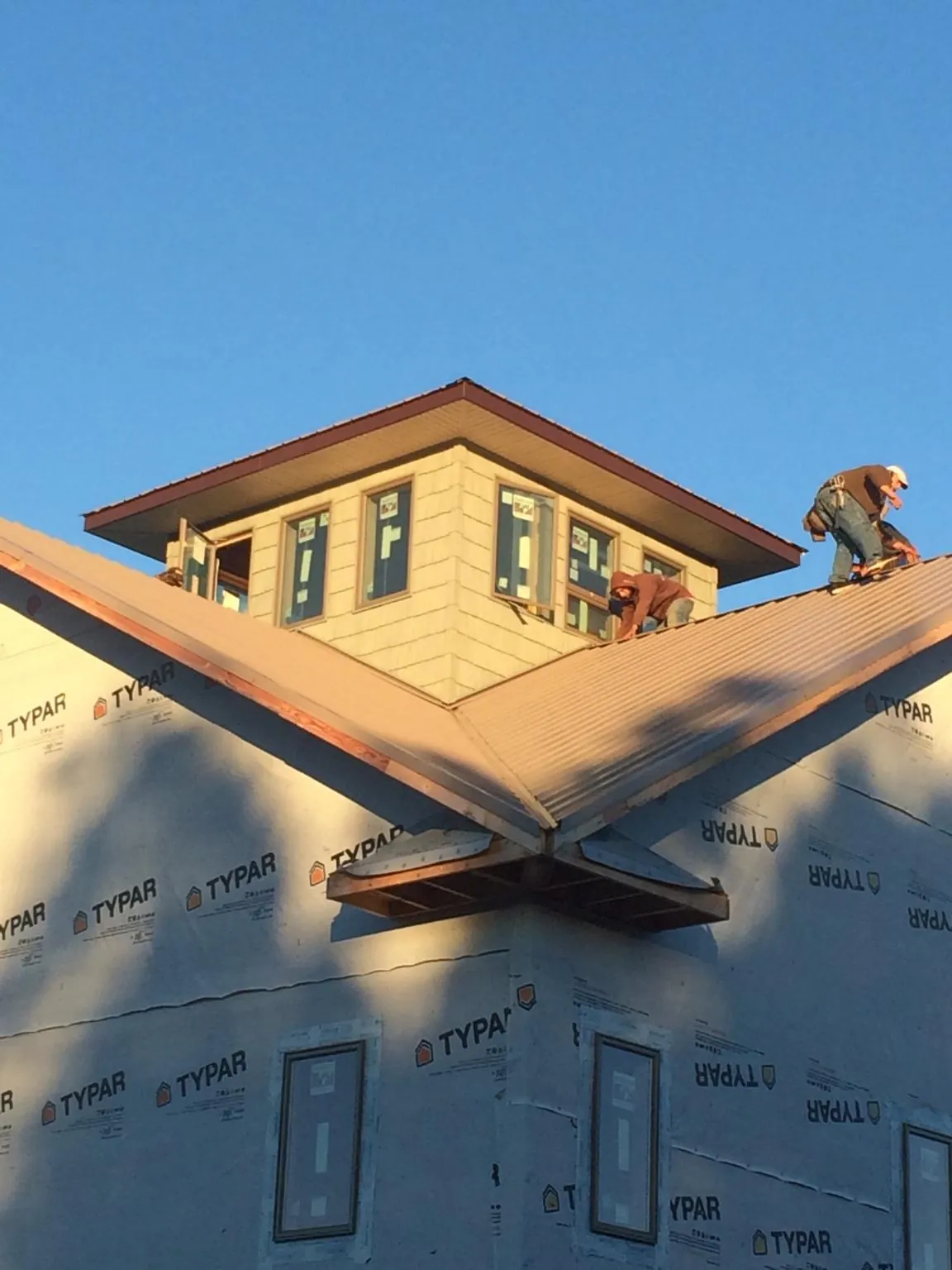 Roofers working around a rooftop cupola on a new metal roof at sunset — Roof Waterproofing in Maple Mount by Roofing Brothers
